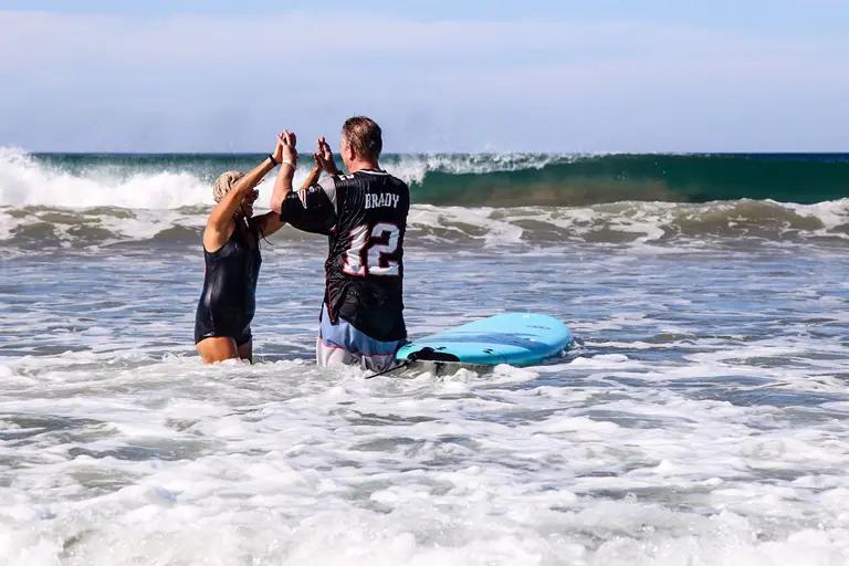 Surf student walking with board on Santa Teresa beach after a coaching session